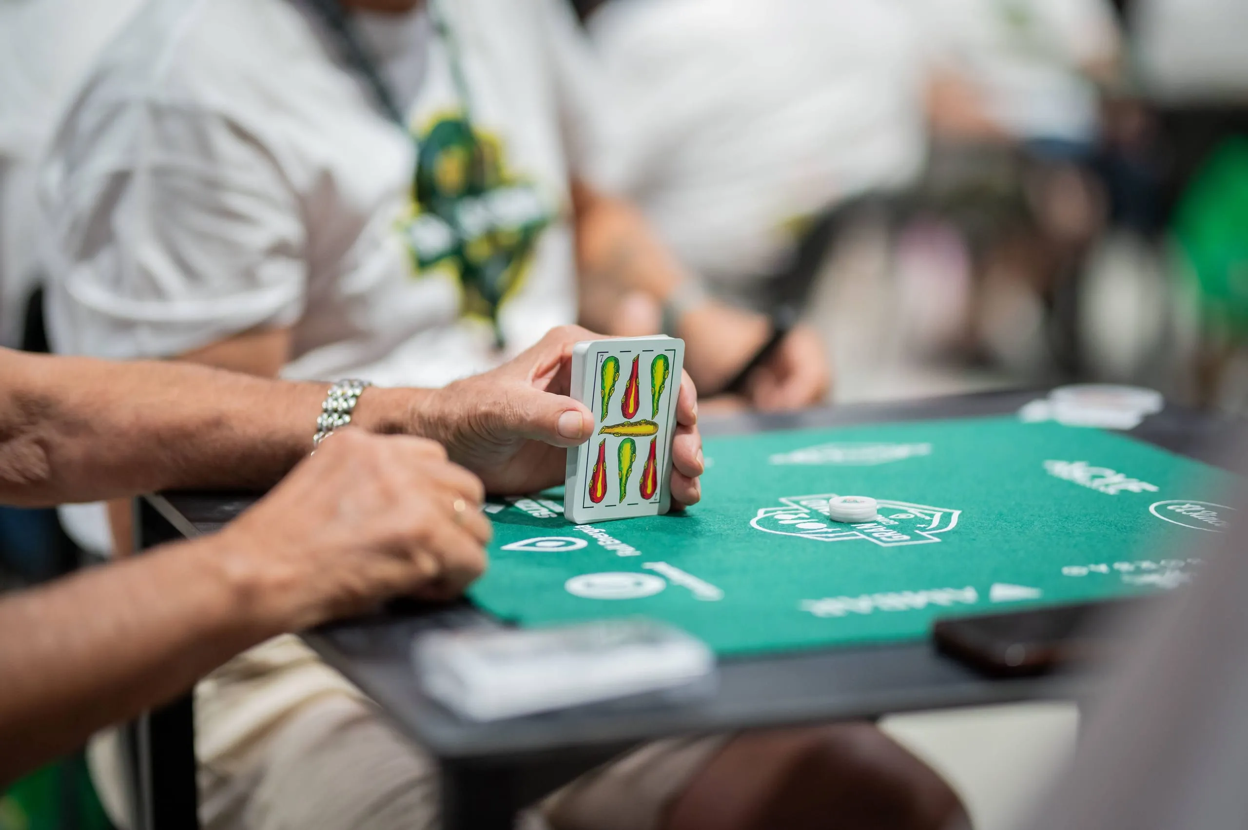 Un jugador sostiene sus cartas españolas abiertas en abanico.